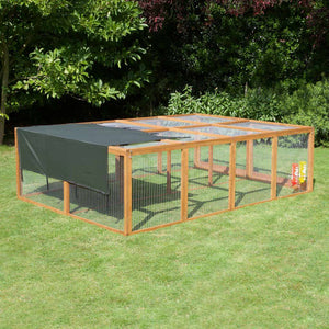 Wooden rabbit run with a green cover on grass with trees in the background