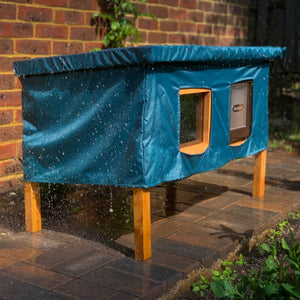 XL cat house rain cover in the garden under a cloudy sky in the rain